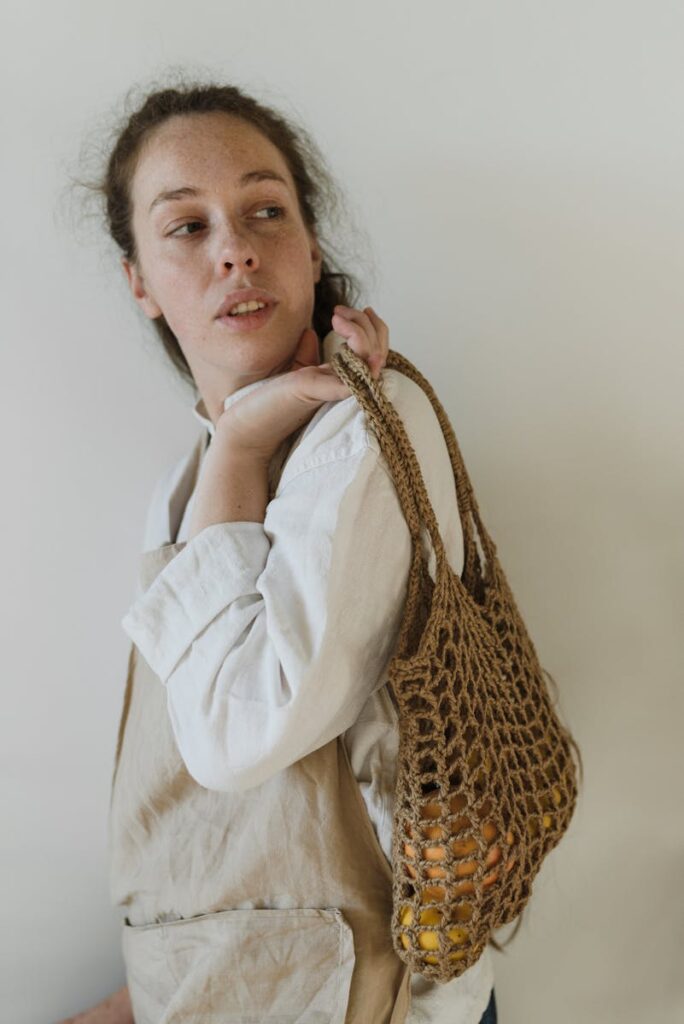 Attentive young lady carrying cotton bag with fresh groceries and looking away