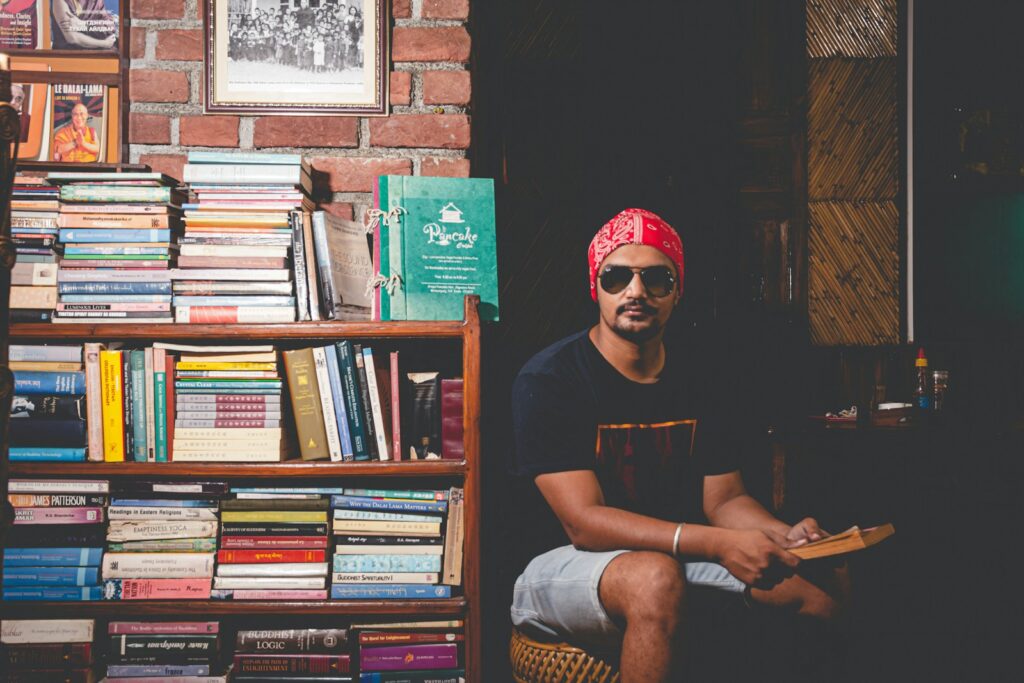 man in black crew neck t-shirt wearing red goggles sitting on brown wooden chair